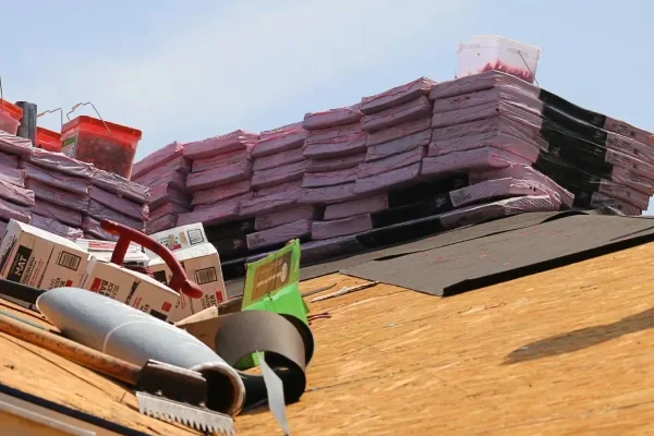 extra2-SRC-Worker-on-bare-rooftop-with-rolled-felt-stacks-of-shingles-and-various-installation-materials-1-scaled-v3